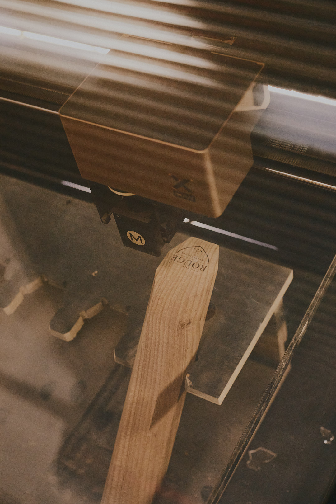 Laser engraving the Rouge marker, close detail showing the engraving process on a finished tee marker.