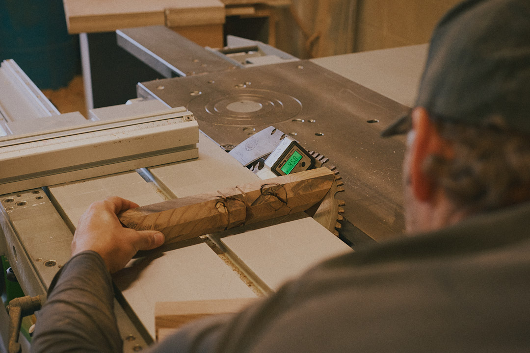 Ben feeding a burl wood piece through the table saw in the studio.