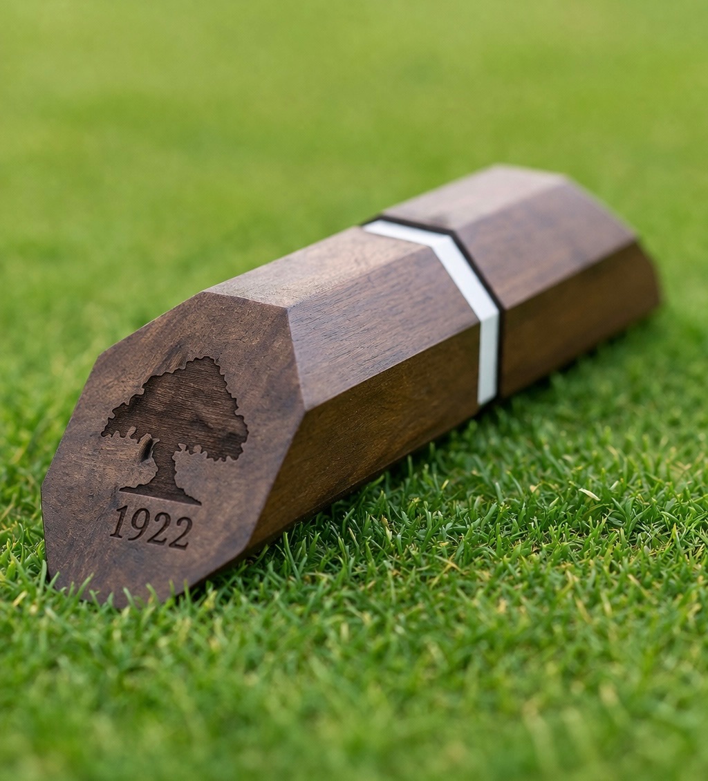 Faceted locally sourced hardwood tee marker with inlay band and engraved Marine Drive Golf Club tree logo and founding year 1922, set on turf.
